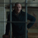 David is seen talking to someone from the outside of a cell with tools hanging on the wall behind him.